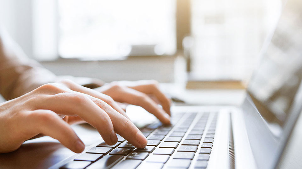 Hands typing on a laptop keyboard.